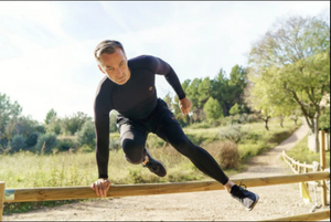 Copper 88 Men's Long Sleeve Compression Shirts in Action Scene On Model Leaping Over a Wooden Fence | ScoutTech Outfitters