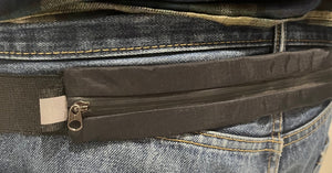 Close-up of a person wearing plaid pants and blue jeans with a visible brand tag.
