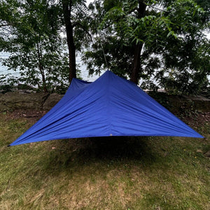 Europe Bound Universal Tarp (150 x 115in) Display Set-up at side of lake outdoors tied between trees and ground stakes | ScoutTech Outfitters
