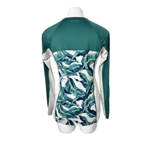 A women's Patagonia long-sleeve rash guard or swim top displayed on a mannequin torso, featuring a solid dark teal upper yoke and shoulders, white raglan sleeves, and a tropical leaf print lower body in teal, navy, and white. | ScoutTech Outfitters